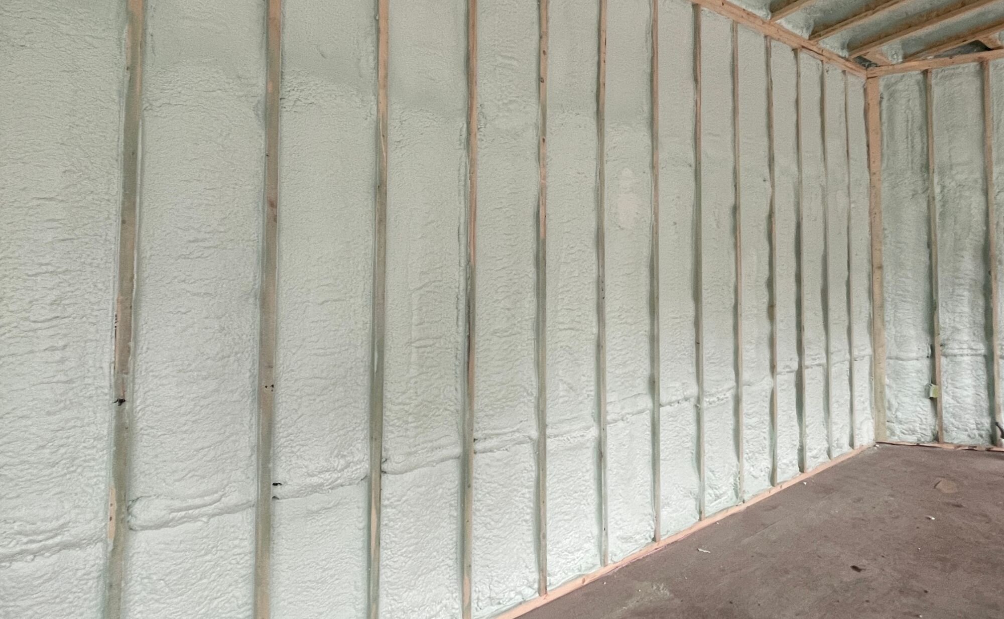 Worker wearing safety equipment while spraying foam insulation